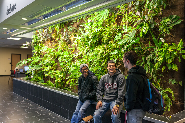 Students stand by the living wall in the atrium building