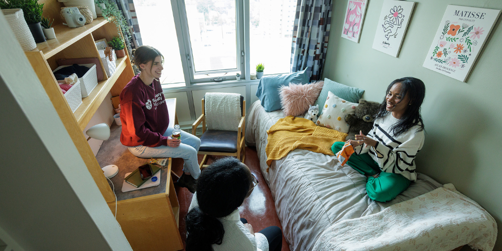 Three students sit in a residence room