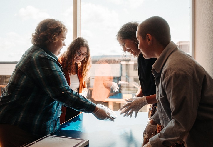 A photo of three students and a professor working on an archival project together.