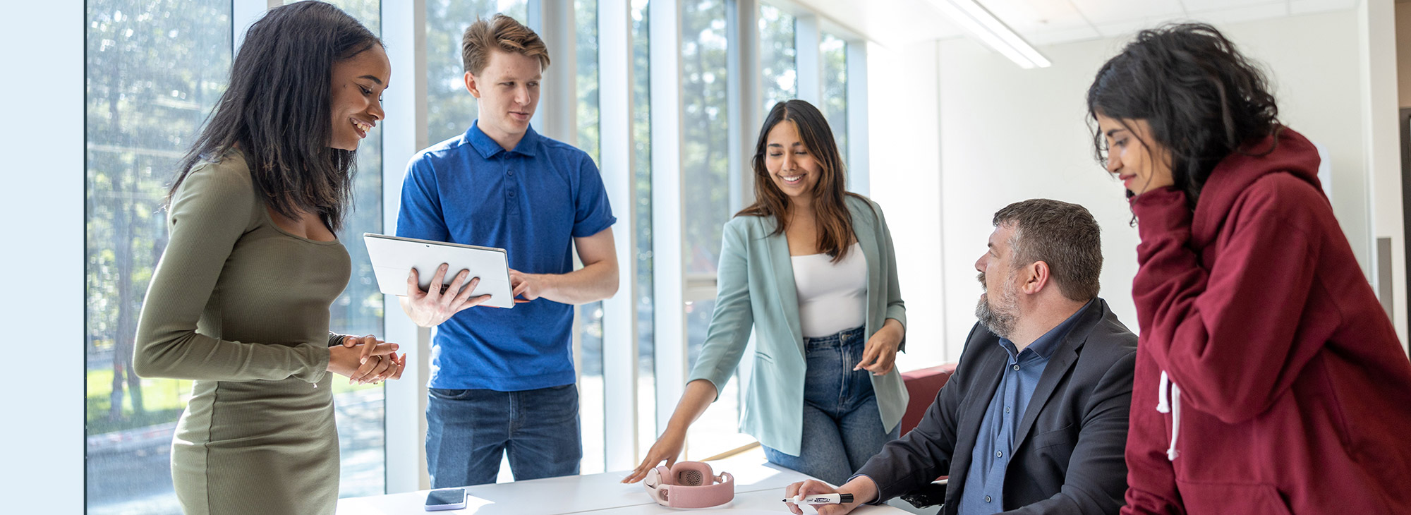 Students standing around a table smiling.