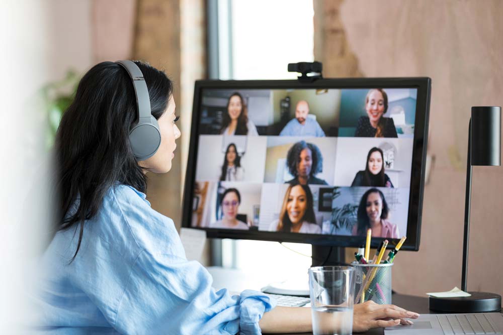 Woman looking at computer screen with a conference call in progress.